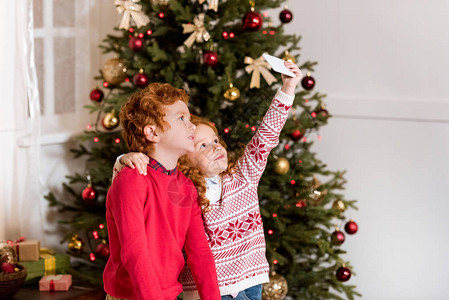 穿着毛衣的小孩在家中圣诞节树附图片