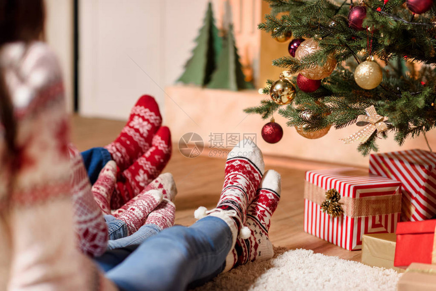 在圣诞节树附近坐在一起的针织袜子中家图片
