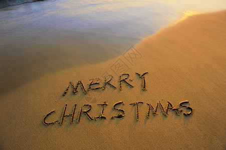 在沙滩上用沙子手写的圣诞快乐背景图片
