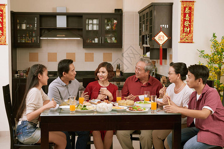 亚洲大家庭在农历新年庆祝活动中交谈和吃东西背景图片
