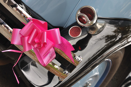 在一辆旧车的后面挂着粉红丝带用于婚礼图片