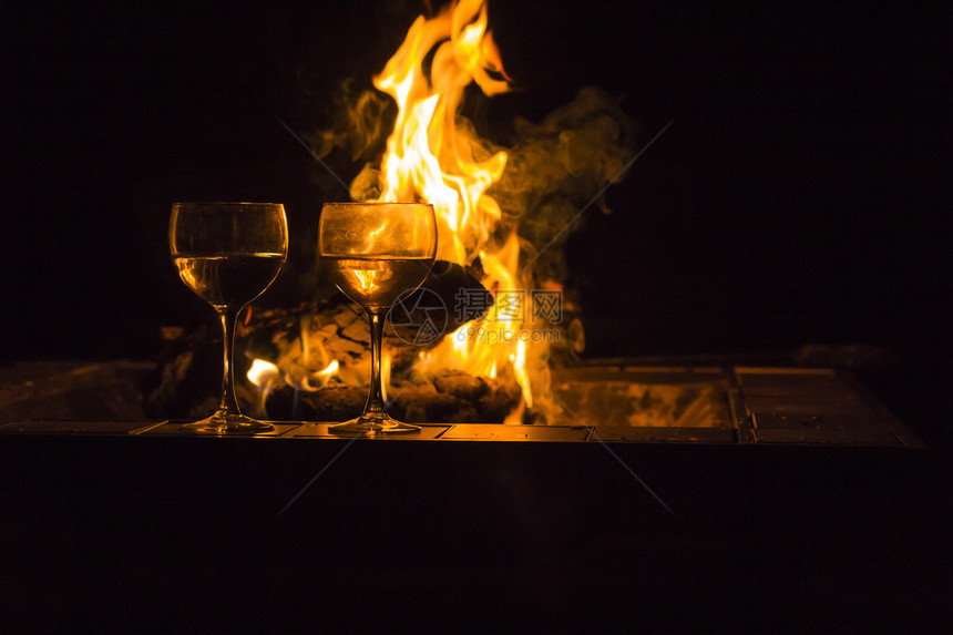 两杯葡萄酒由营火旁的两杯红酒在这张闪亮图片
