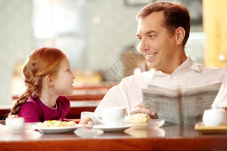 小女儿和父亲坐在咖啡馆里图片