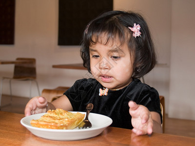 小美洲土著女孩在咖啡店里吃一小片quic图片