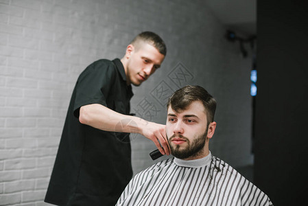 专业理发师在理发店为一位留着胡子的客户剪头发图片