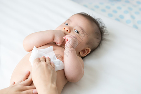 妈在更换尿布或尿布以及擦手脸或腿时用湿纸巾清洁和擦拭身体婴儿背景图片