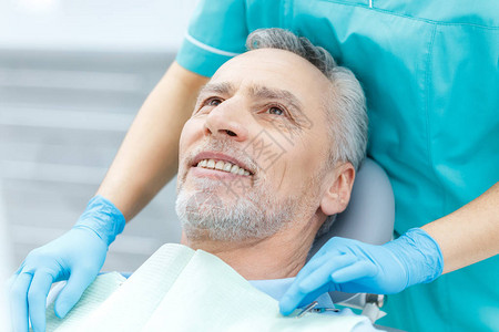 戴医疗手套微笑的成熟病人和牙科医图片
