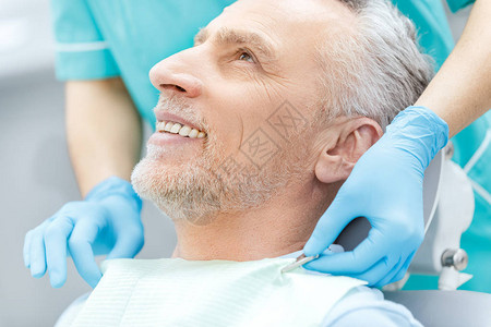 戴医疗手套微笑的成熟病人和牙科医背景图片