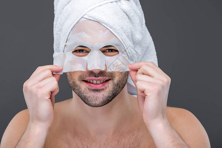带着毛巾和Collagen面罩的可喜的胡须男子图片