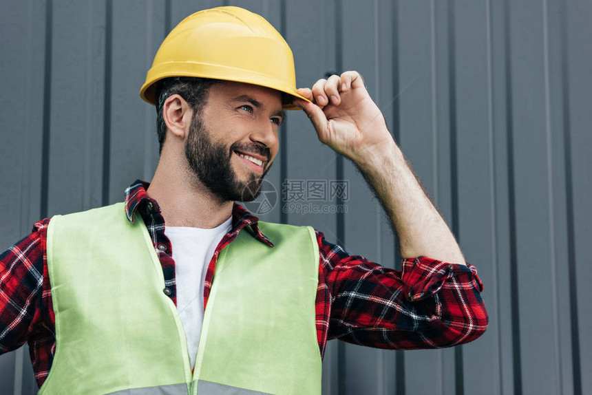 身穿安全背心和头盔的男微笑建筑工图片