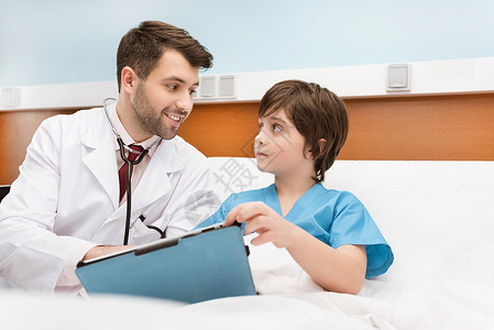 微笑的医生和小男孩病人拿着剪贴板图片