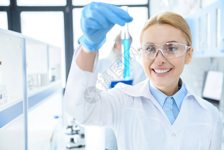 在保护眼镜中微笑化学家在实验室内用试图片