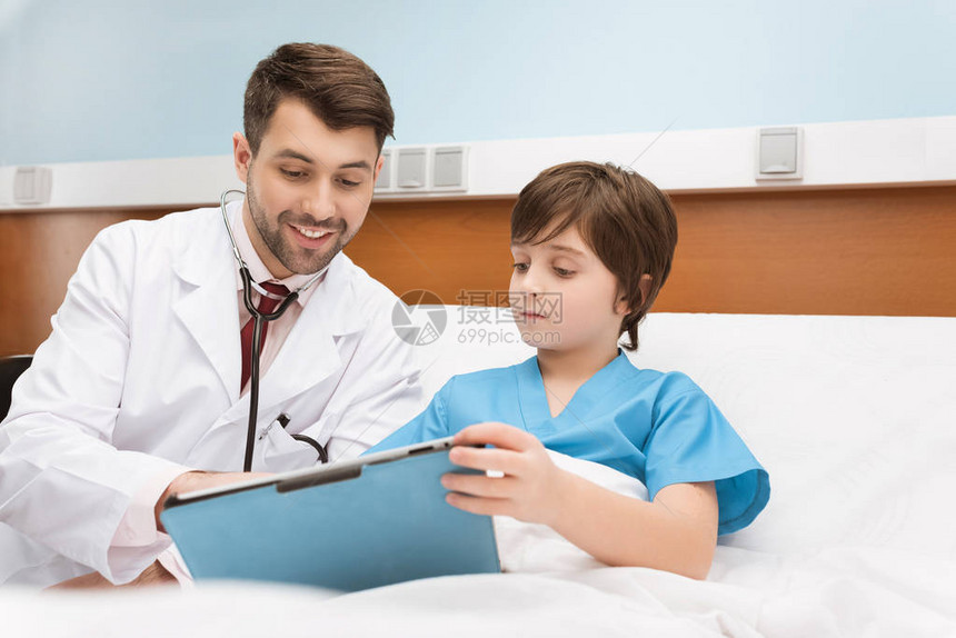 微笑的医生和小男孩病人把剪贴板图片