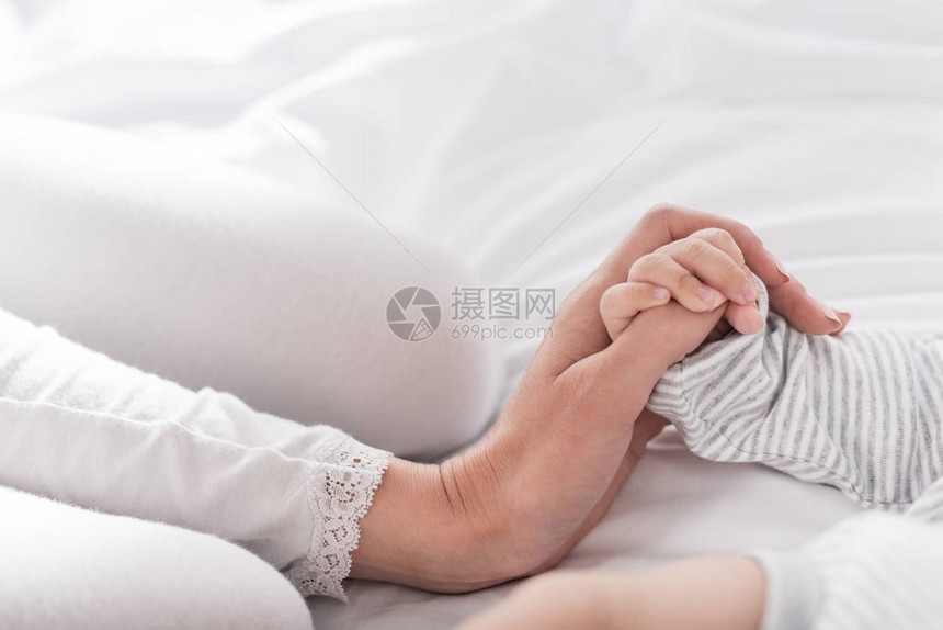 母亲握着婴儿手的切图片