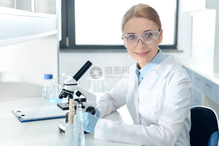 戴着防护镜的微笑专业科学家在化学实验室图片