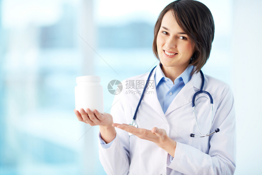 一个微笑着的药剂师拿着一瓶药丸指图片