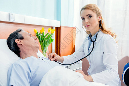 躺在床上的中年病人和在医院用听诊器图片