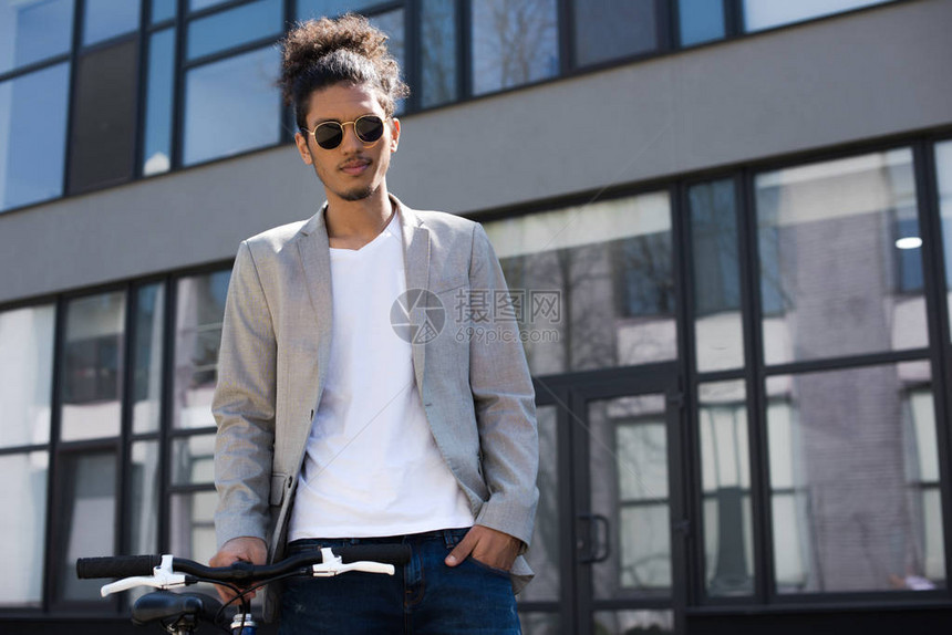 身戴太阳眼镜的年轻英俊的非洲男子站在街上骑图片