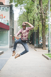 年轻英俊的非洲黑人男子在城市街道上跳跃图片