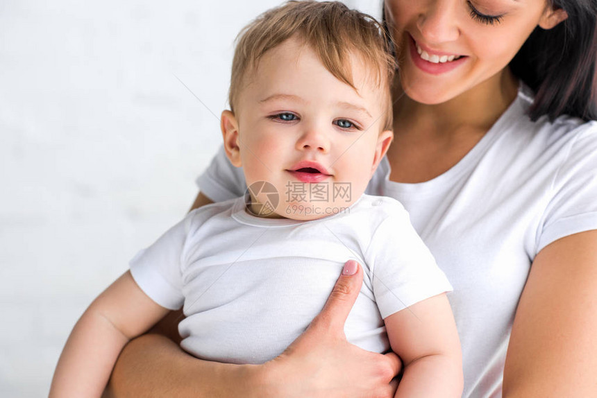 微笑的母亲和可爱的小宝在家中手图片
