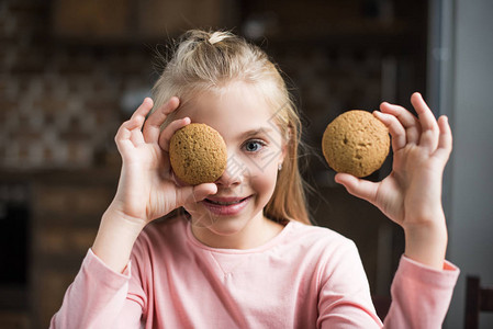微笑的孩子用饼干遮住眼睛的模糊眼神在家图片