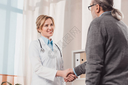 白大衣上有微笑的医生和诊所有病人握图片