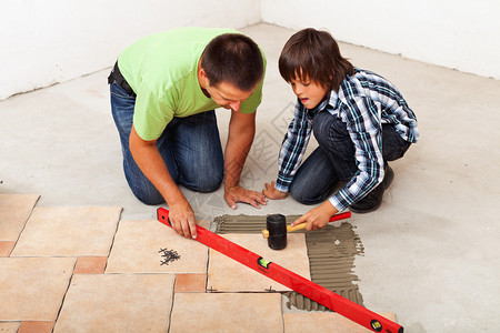 男人和男孩一起铺设陶瓷地砖图片
