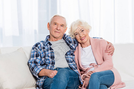 面带微笑的年长妻子和丈夫在家中沙发上休息时看着图片