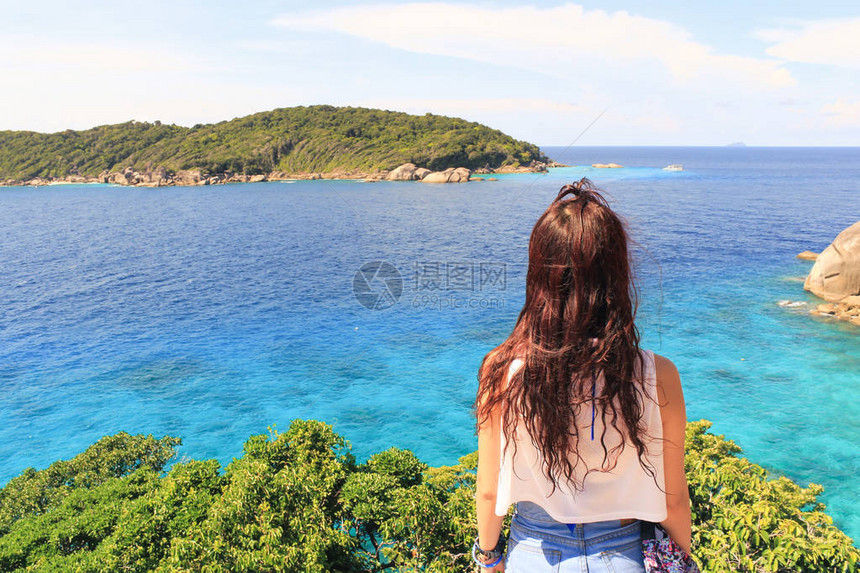 一个年轻的旅行者女孩坐在下龙湾的山顶上图片