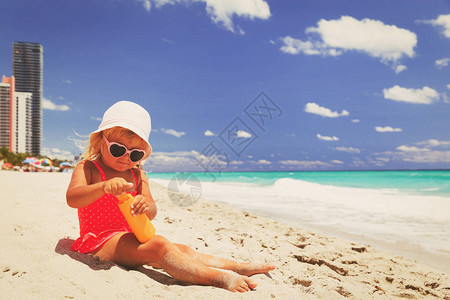 防晒海滩上涂防晒霜的可爱小女孩图片