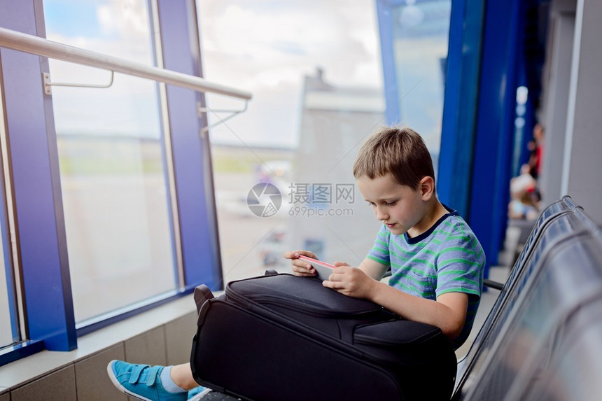 7岁男孩在机场等待飞机玩智能电话游戏图片