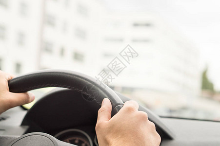 在城市里开车的人司机双手握着方向盘公路旅行旅行或通勤概念背景图片