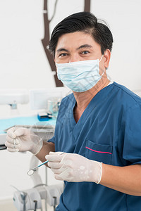 一位拥有口腔仪器的英俊牙医的垂直肖像画Stomatat图片