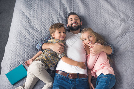 快乐的父亲和小孩在家里一起躺在床上的眼神中图片