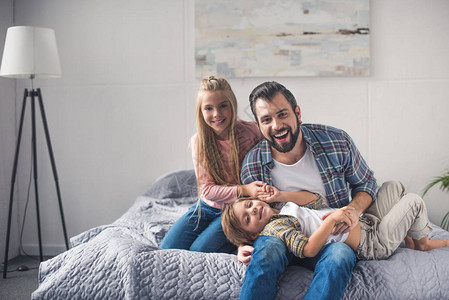 快乐的父亲和小孩在家一起睡在床上图片
