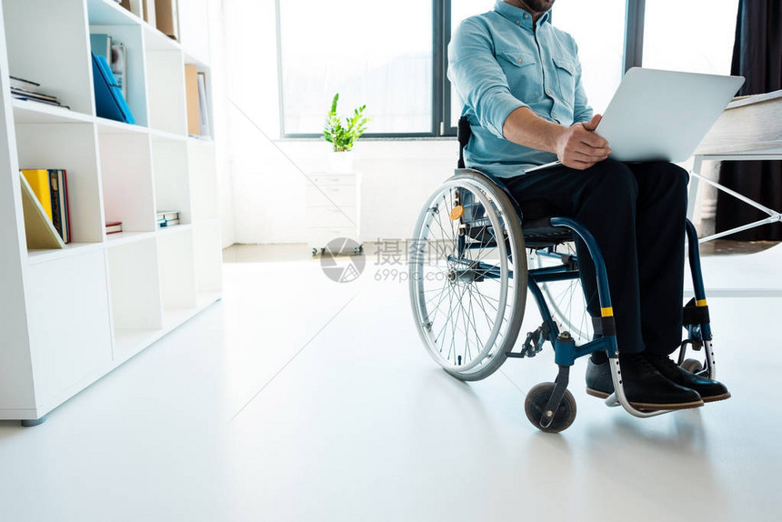 使用办公室膝上型电脑坐在轮椅上的商人图片