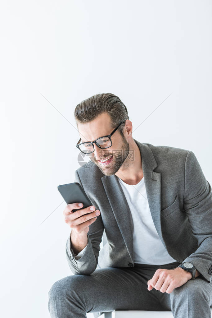 穿着灰色西装的优雅时尚男子使用智能手机图片