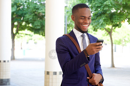 一位快乐的年轻商人在手机上阅读短信的近距离肖像图片
