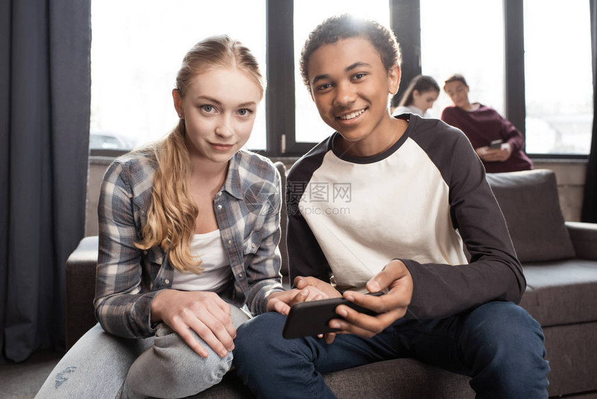 快乐的青少年情侣在沙发上使用智能手机图片