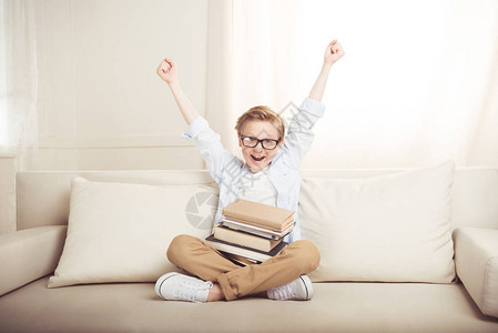 快乐的小男孩有一堆书坐在图片