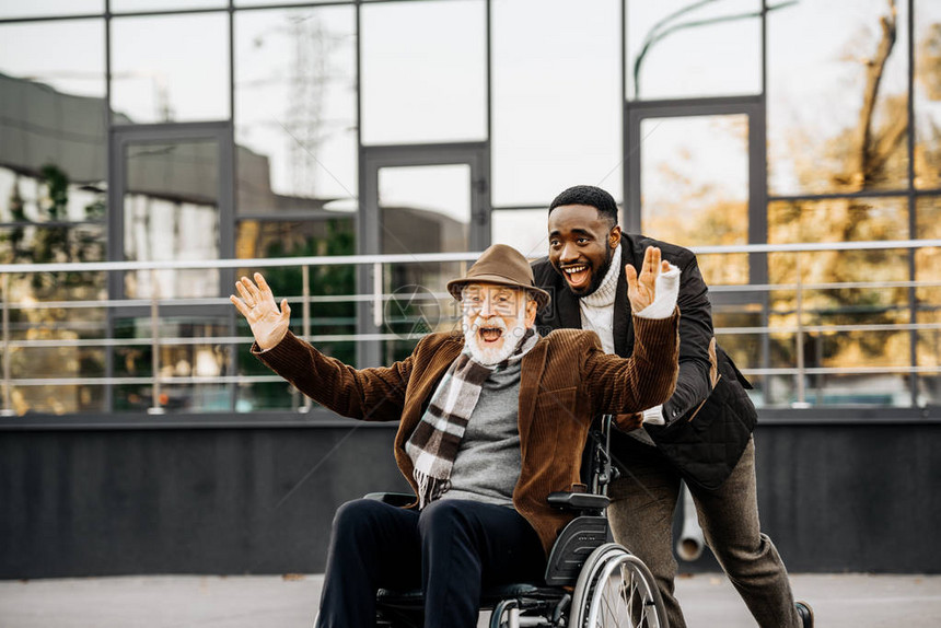 坐在轮椅上幸福快乐的老年残疾人和在街上玩乐图片