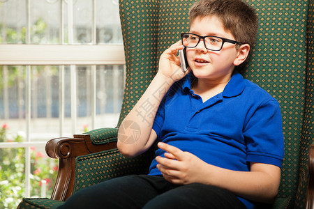 戴眼镜的可爱金发小男孩在电话上图片