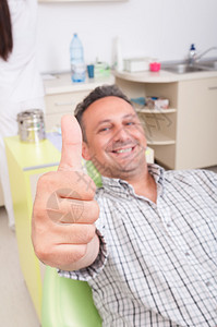 放松的男病人坐在牙医椅子上显示大图片
