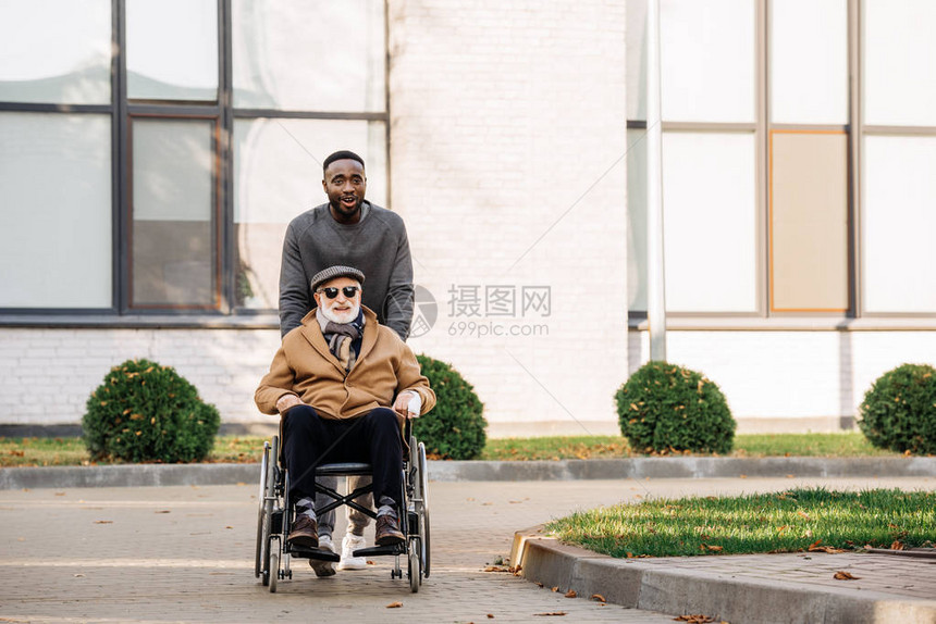 坐在轮椅上幸福快乐的老年残疾人和非洲裔美国人一图片