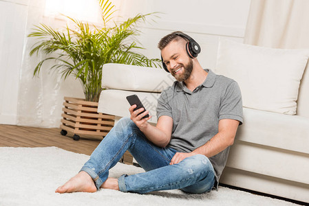 在家使用智能手机和听音乐的耳机用耳机充耳不响的图片