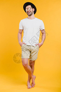 穿着短裤和太阳镜的年轻赤脚男子双手插在口袋里站着图片