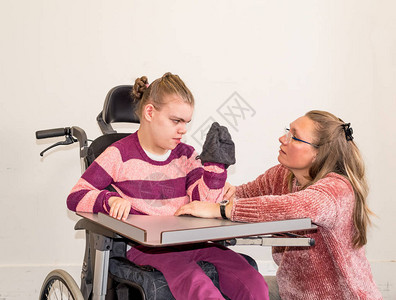 一名坐在轮椅上的残疾儿童正在接受帮助个人卫生的志愿护图片