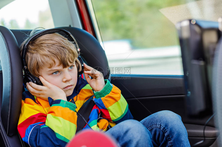 金发小男孩在家庭度假期间驾驶长车时用耳机看电视或DVD图片