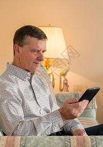 坐在阳光下的退休老人在客厅阅读eBook图片