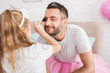 金发女儿用刷子给父亲化妆图片